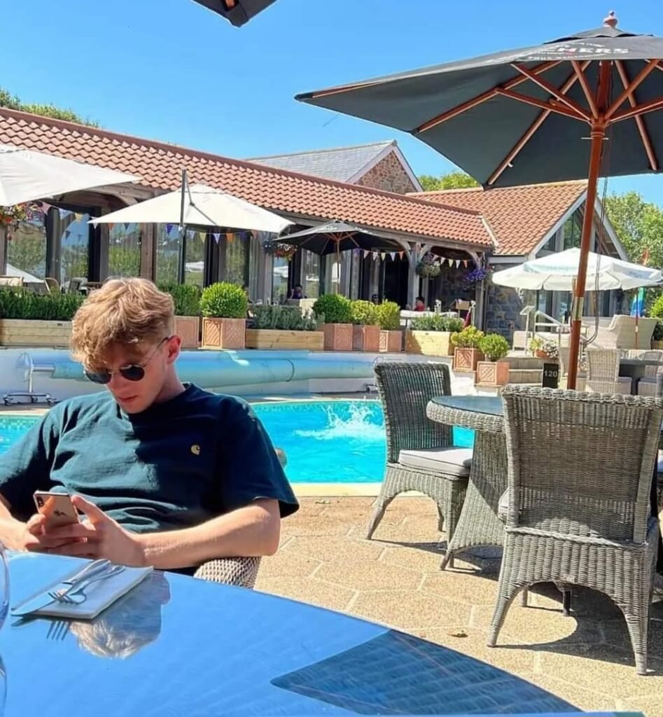 A picture of Blaze Vile sat on his phone in front of a pool